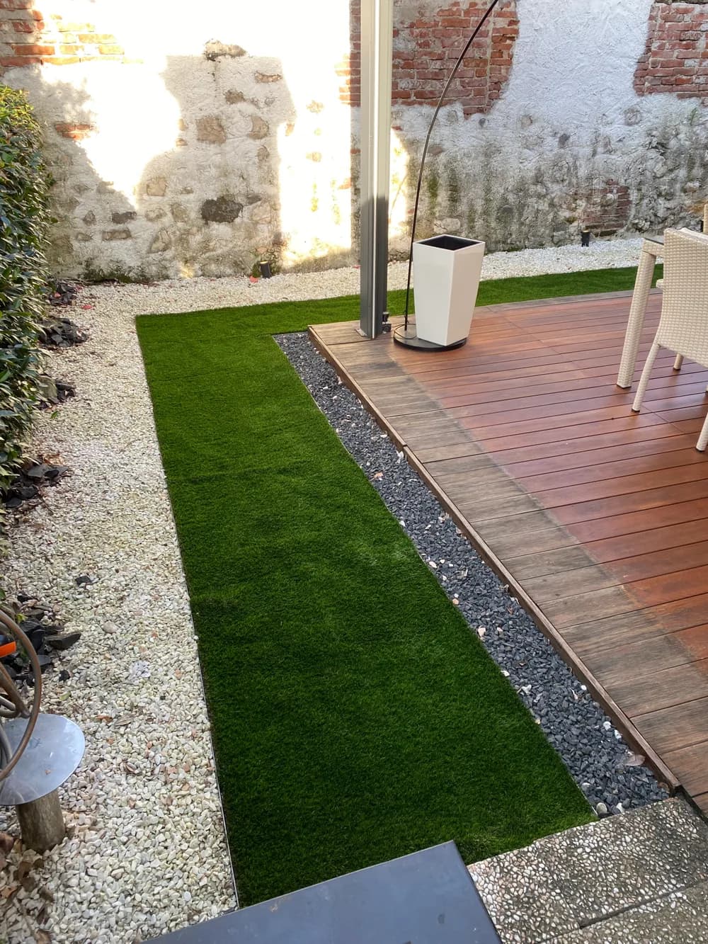 Terrazza in legno affiancata da verde e bordure in ghiaia
